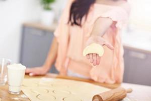 Young woman trying to make pierogi in kitchen photo