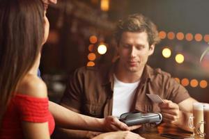 linda pareja en una cita en el café pagando con tarjeta de crédito foto