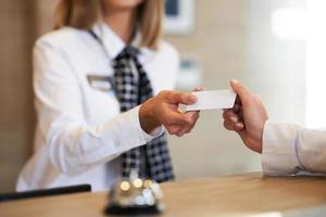 Receptionist giving key card to businesswoman at hotel front desk photo