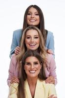 Three women in pastel suits posing over white background photo