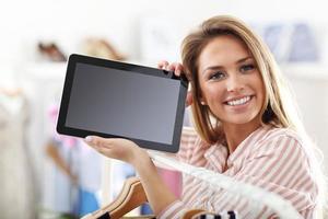 Happy woman in clothes shop holding tablet photo