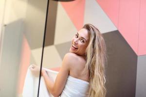 Beautiful blonde Caucasian woman posing in bathroom with wet hair photo