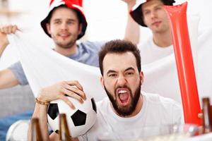 Happy male friends cheering and watching sports on tv photo