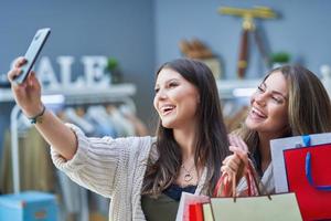 Group of happy friends during shopping with phone photo