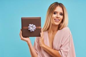 Beautiful adult woman posing over blue background with present photo