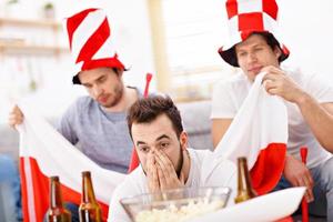 Happy male friends cheering and watching sports on tv photo