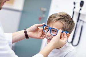 Child optometry male optometrist optician doctor examines eyesight of little boy photo