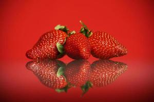 Three strawberries against red background photo