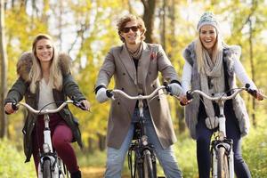 grupo de amigos en bicicleta en el bosque durante el otoño foto