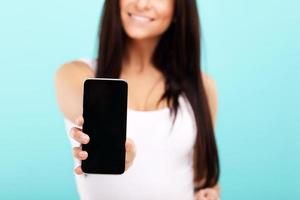 Woman using smartphone against blue wall background photo