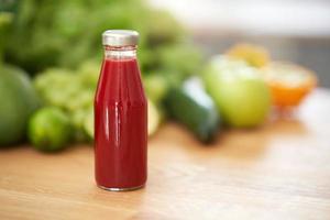 Bottle of smoothie oresh green fruit and vegetables on wooden counter photo