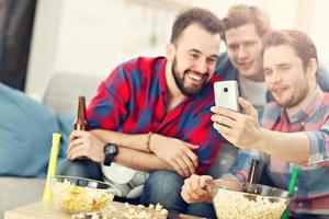 Happy male friends cheering and watching sports on tv photo