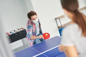 Couple of students wearing masks while playing table tennis in the campus photo