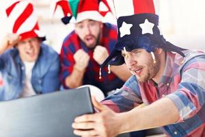 Happy male friends cheering and watching sports on tv photo