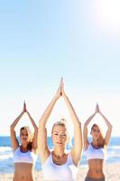 Group of women practising yoga on the beach photo