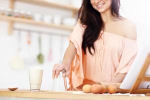 Young woman trying to make pierogi in kitchen photo