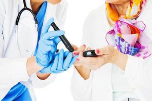 Doctor Examining Senior Woman's Blood Sugar Against White Background photo