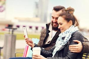 Young couple with shopping bags and smartphone photo