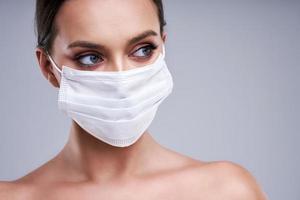 Portrait of beautiful woman in mask on gray background photo