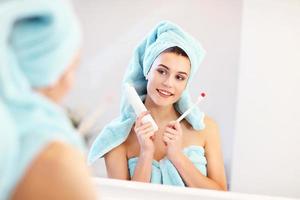 mujer joven lavando los dientes en el baño por la mañana foto