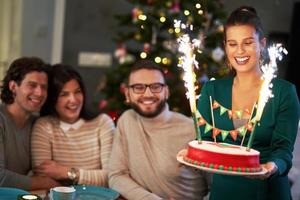 Group of friends celebrating Christmas at home with fancy cake photo