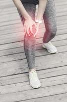 Female athlete runner touching knee in pain outdoors photo