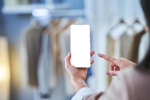 Woman holding phone in clothes store with blank space photo