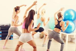 Group of happy people with coach dancing in gym photo