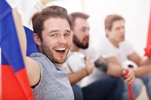 Happy male friends cheering and watching sports on tv photo