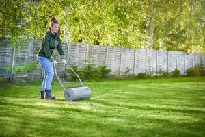 Woman working with lawn roller in the garden photo