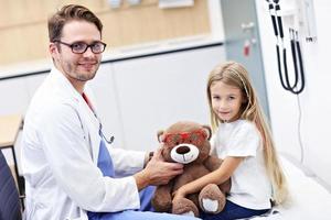 Child male optometrist examines eyesight of little girl photo