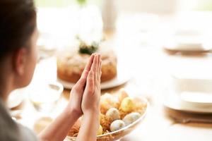 mujer adulta bendiciendo la comida de pascua en casa foto