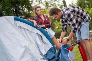 Young nice couple having fun on camping setting up tent photo