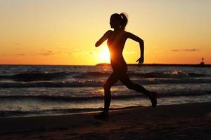 mujer corriendo sola en el hermoso atardecer en la playa foto