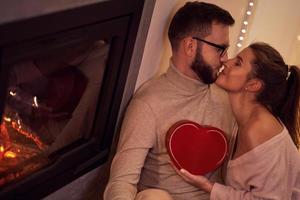 Adult couple with present over fireplace photo