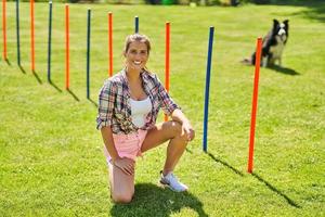 Border collie dog and a woman on an agility field photo