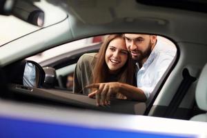 Adult couple choosing new car in showroom photo