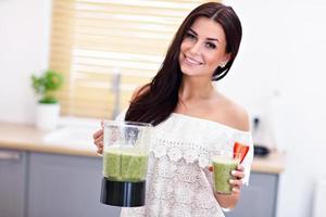 Fit smiling young woman preparing healthy smoothie in modern kitchen photo