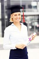 Happy graduate standing outside modern building photo