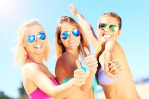 Group of women showing ok signs on the beach photo