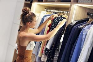 Beautiful woman thinking what to dress in walk-in closet photo