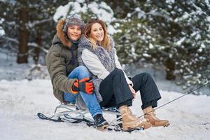 Couple having fun with sledge on snow in winter photo