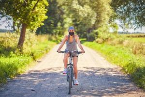 mujer joven en bicicleta en el campo con una máscara foto