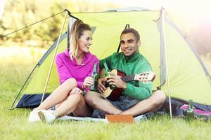 Couple camping in forest and playing guitar photo