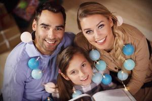Family reading story book together under Christmas tree photo