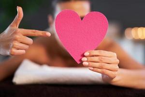 Relaxed woman waiting for a back massage and holding heart photo