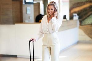 Businesswoman using smartphone in the modern hotel lobby photo