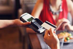 personas pagando en restaurante con lector de tarjeta de crédito foto