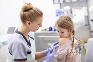 Brave little girl receiving injection or vaccine with a smile photo