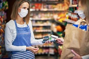 Adult woman in medical mask picking up order in grocery store photo